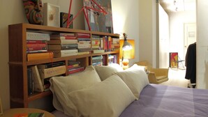Ein Schlafzimmer mit Bett, Bücherregal, Lampe und Tür.