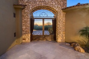 Enter through a traditional stone archway, flanked by walls in contrasting tones, into a well-maintained outdoor space.