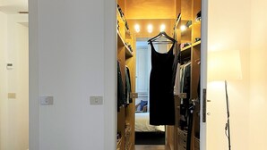 A hotel room with a bed, a walk-in closet with hanging clothes, and a bedside table. - APARTMENT 6 CASTEL SANT'ANGELO RELAIS (Roma)