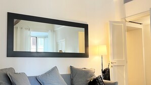 A modern living room with a grey sofa, a large mirror, and a geometric patterned floor. - APARTMENT 6 CASTEL SANT'ANGELO RELAIS (Roma)