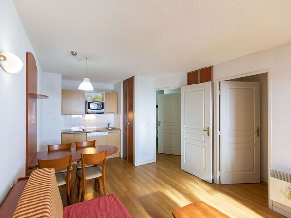 Un espacio habitable compacto con kitchenette, comedor y dos dormitorios.