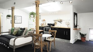 Un espacio habitable moderno y abierto con cocina, comedor y un dormitorio.