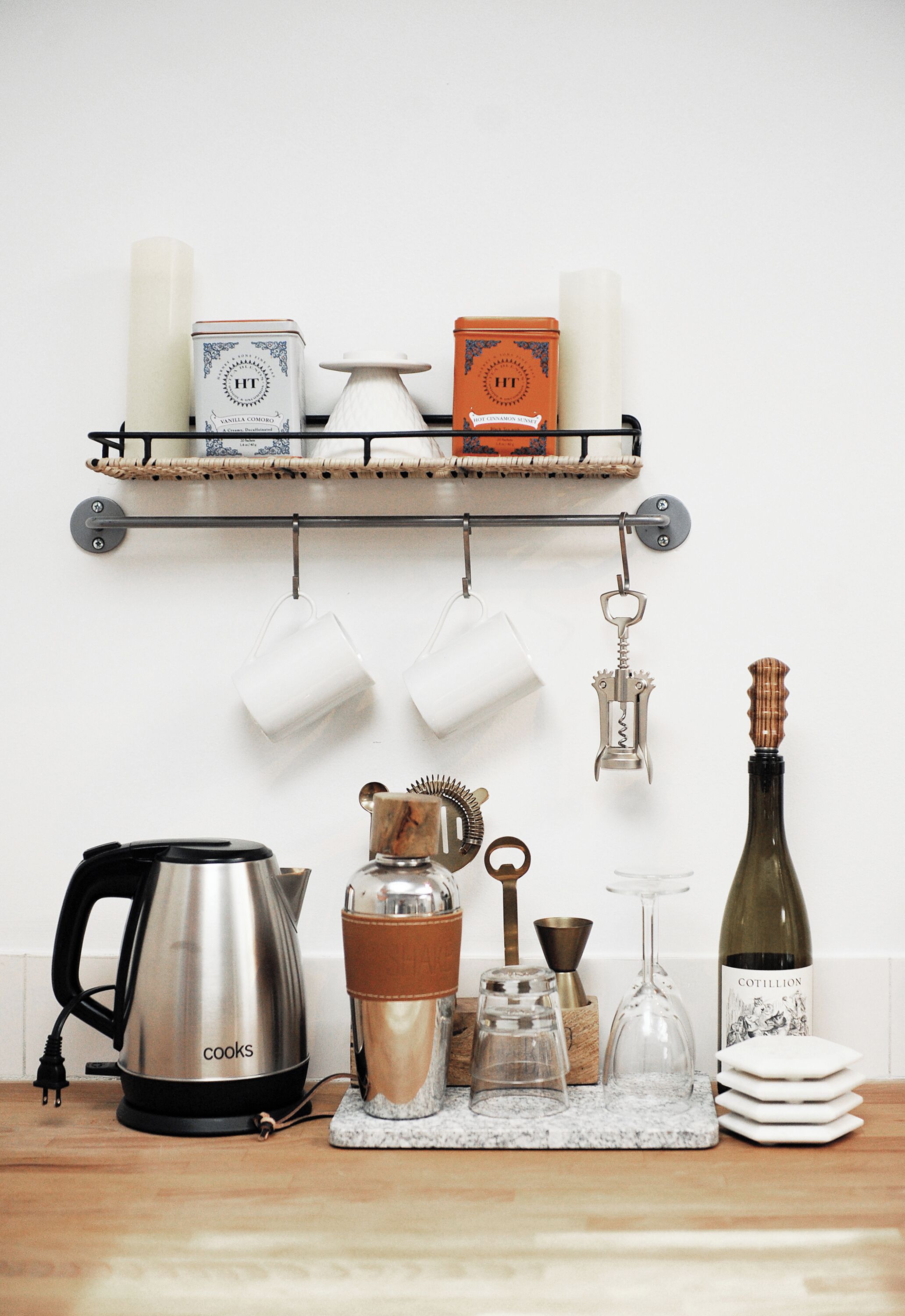 Una encimera de cocina con una tetera, una botella de vino y diferentes utensilios de cocina.