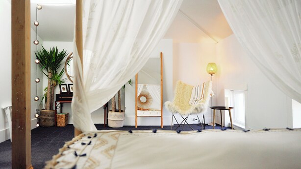 Un dormitorio con cama con dosel, una silla, una lámpara y un espejo.