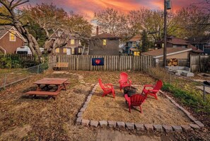 A backyard with a picnic table, red chairs, and a wooden fence.