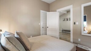 Ein Schlafzimmer mit Bett, Kissen, einer Tür und einem Spiegel.
