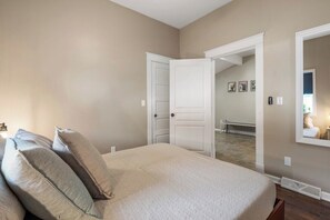 A bedroom with a bed, pillows, a door, and a mirror.