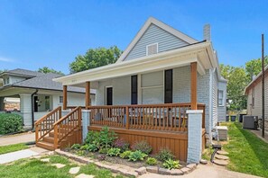 A single-story house with a front porch, a small deck, and a garden area.