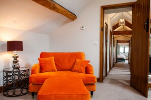 A room with a sofa, a lamp, and a hallway leading to another room.