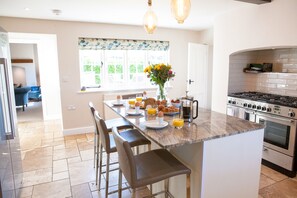 A modern kitchen with a central island, bar stools, a dining table, and a large window with a view. - Marrington Farmhouse, Montgomery , Shropshire (Montgomery)