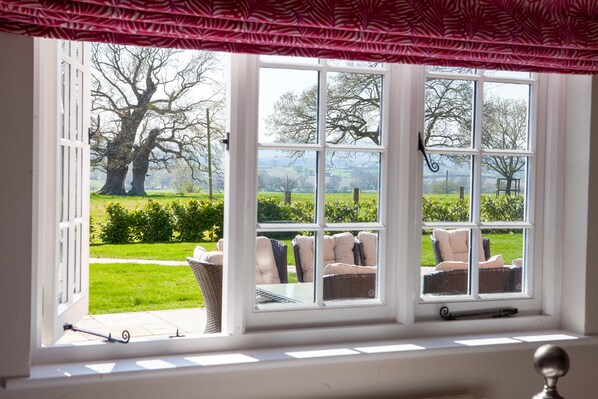 A room with a large window overlooking a garden with chairs and a table.