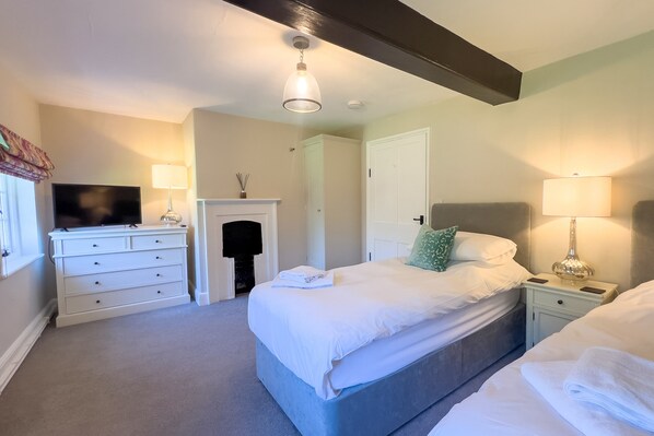 A hotel room with a bed, bedside tables, a TV, and a fireplace.