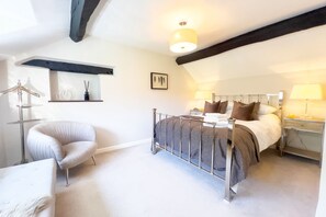 A bedroom with a bed, bedside tables, a chair, and a hanging light fixture.