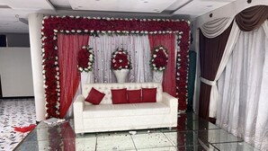 Une pièce avec un canapé blanc, des coussins rouges et des compositions florales.