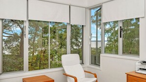 A room with large windows, a white chair, a wooden table, and a printer. - Bayview on Bayview, Hyams Beach (Hyams Beach)