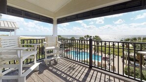 Ein überdachter Außenbereich mit Pool, weißen Stühlen und Blick aufs Meer.