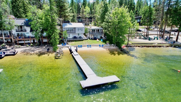 A lakeside property with a dock extending into the water, surrounded by trees and a building with a balcony. - Annie's Place-Lakefront-Shared dock w/Almost Heaven-Rent both for a 6-room getaway for large groups! (McCall)