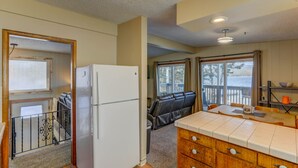 A compact kitchen with a refrigerator, a dining area with a table and chairs, and a view through a window. - Annie's Place-Lakefront-Shared dock w/Almost Heaven-Rent both for a 6-room getaway for large groups! (McCall)
