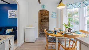 A cozy dining area with a stone archway, a clock, and a motivational quote on the wall. - Cherry Orchard Cottage by Interhome (Mevagissey)