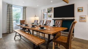 A dining room with a wooden table, leather chairs, a bench, and a fireplace.