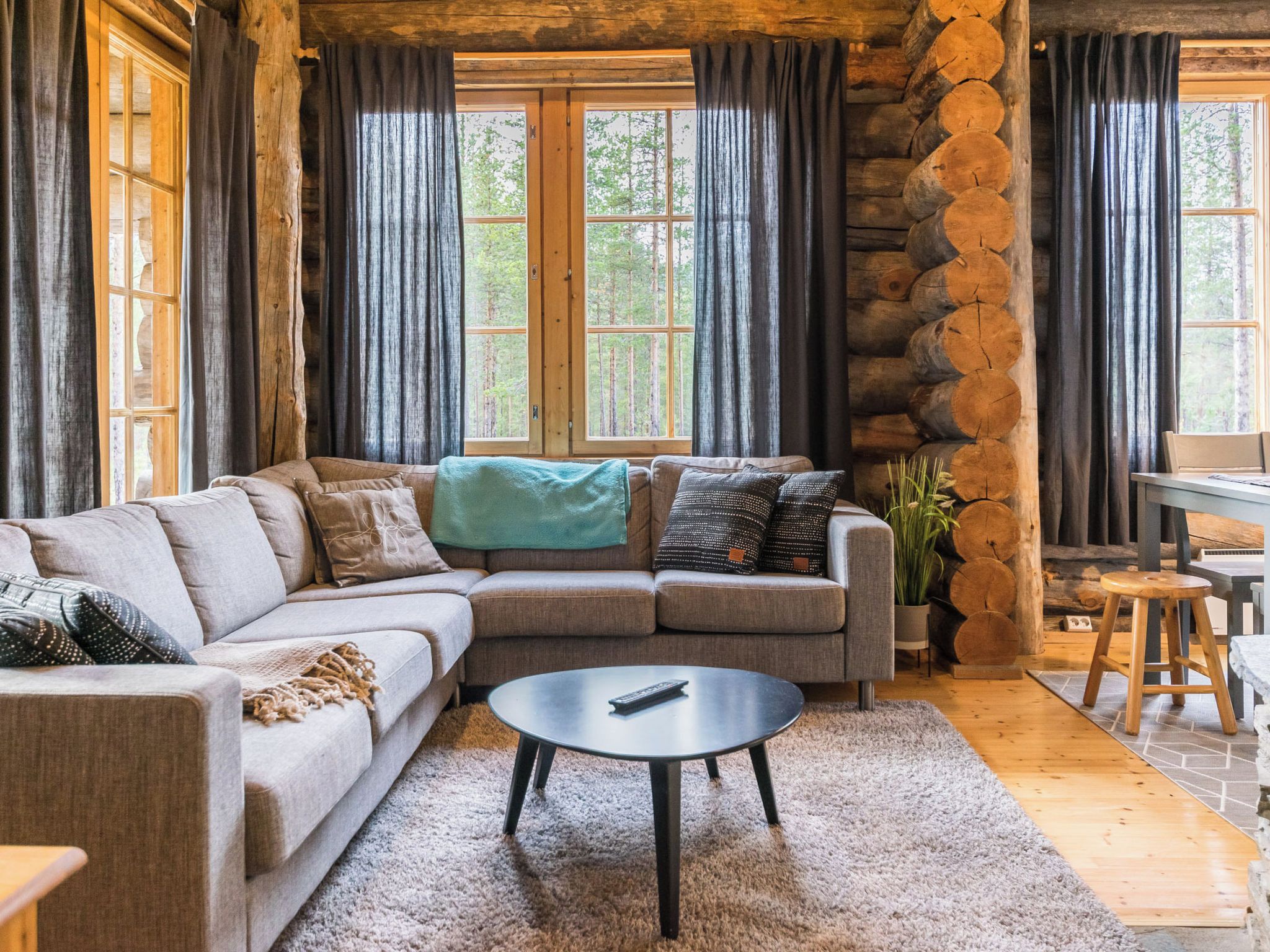 A cozy log cabin interior with a sectional sofa, a round coffee table, and a stone wall.