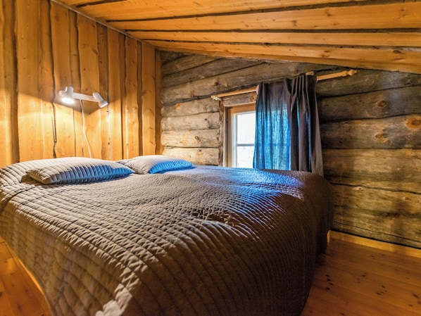 A log cabin bedroom with a bed, a desk lamp, and a window with curtains. - Kultatunturi by Interhome (Pelkosenniemi)