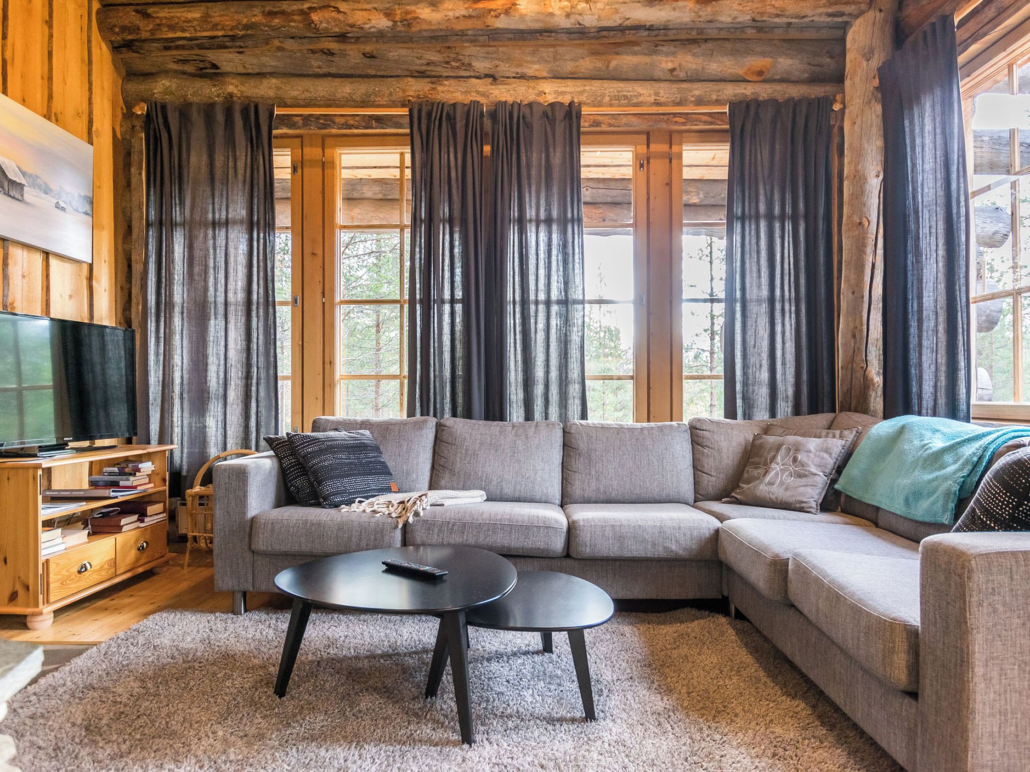 A cozy living room with a sectional sofa, a coffee table, and a TV on a wooden stand.