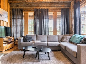 A cozy living room with a sectional sofa, a coffee table, and a TV on a wooden stand.