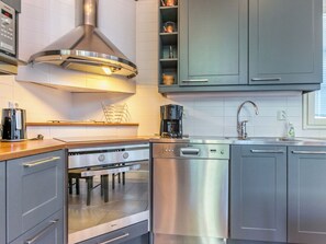 Una cocina moderna con electrodomésticos de acero inoxidable, incluyendo estufa, horno y lavavajillas, y armarios grises.
