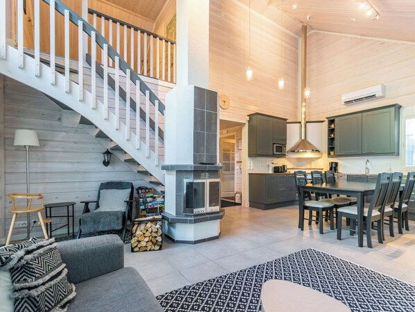 Amplia sala de estar con escalera, chimenea, comedor y cocina.