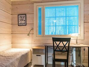 Une pièce comprenant un lit, un bureau, une chaise, une fenêtre avec des stores et un tableau accroché au mur.