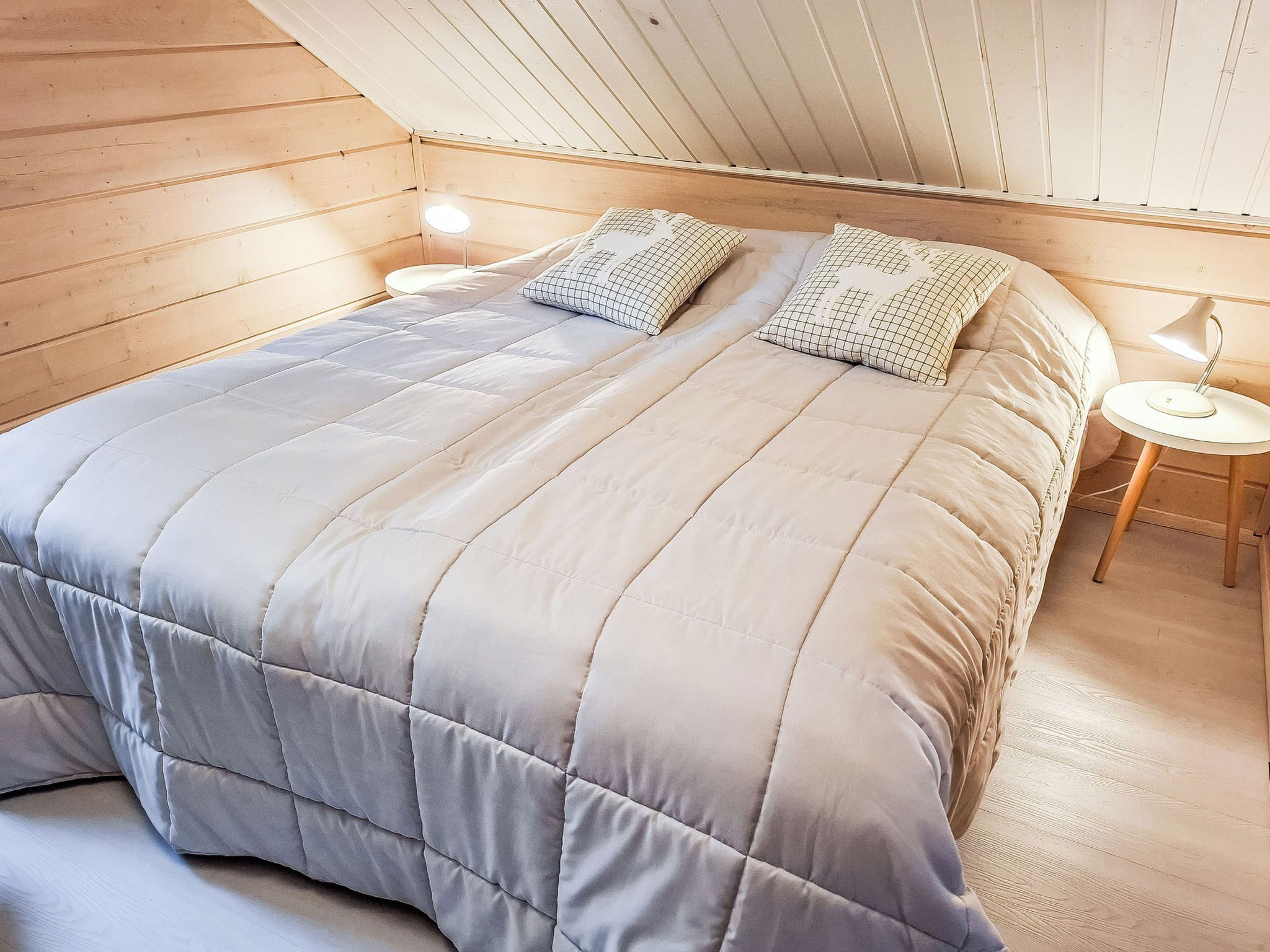 A bedroom with a large bed, two bedside tables, and a sloped ceiling.