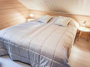 A bedroom with a large bed, two bedside tables, and a sloped ceiling.
