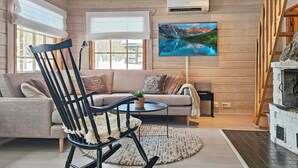 Una sala de estar acogedora con un sillón mecedora, un sofá y un televisor montado en la pared.
