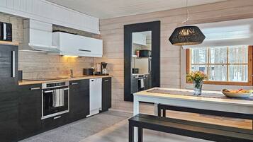 A modern kitchen with a central island, a dining area with a bench, and a large window with a view of trees.