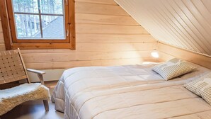 Un dormitorio acogedor con una cama grande, una silla de madera y una ventana con vistas a árboles.
