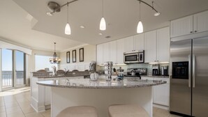 A spacious kitchen with a large island, stainless steel appliances, and pendant lighting. - Luxurious 4 bedroom oceanfront condo in the most prestigious building in OC, (Ocean City)