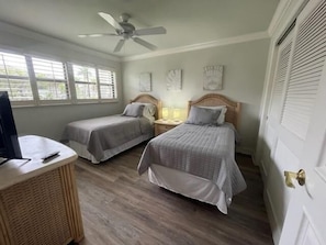 A bedroom with two single beds, a ceiling fan, a desk with a computer, and a window with blinds. - 3BR Marco Island home with heated pool, WiFi, and full kitchen (Marco Island)
