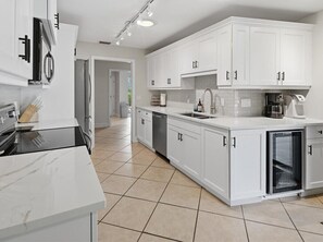 A modern kitchen with white cabinetry, a built-in oven, and a coffee machine.