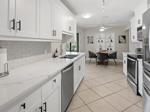 Una cocina moderna con armarios blancos, una isla central y un comedor con mesa y sillas.