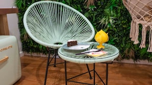 Una habitación con una silla verde y una pequeña mesa con un pastel y un objeto amarillo.
