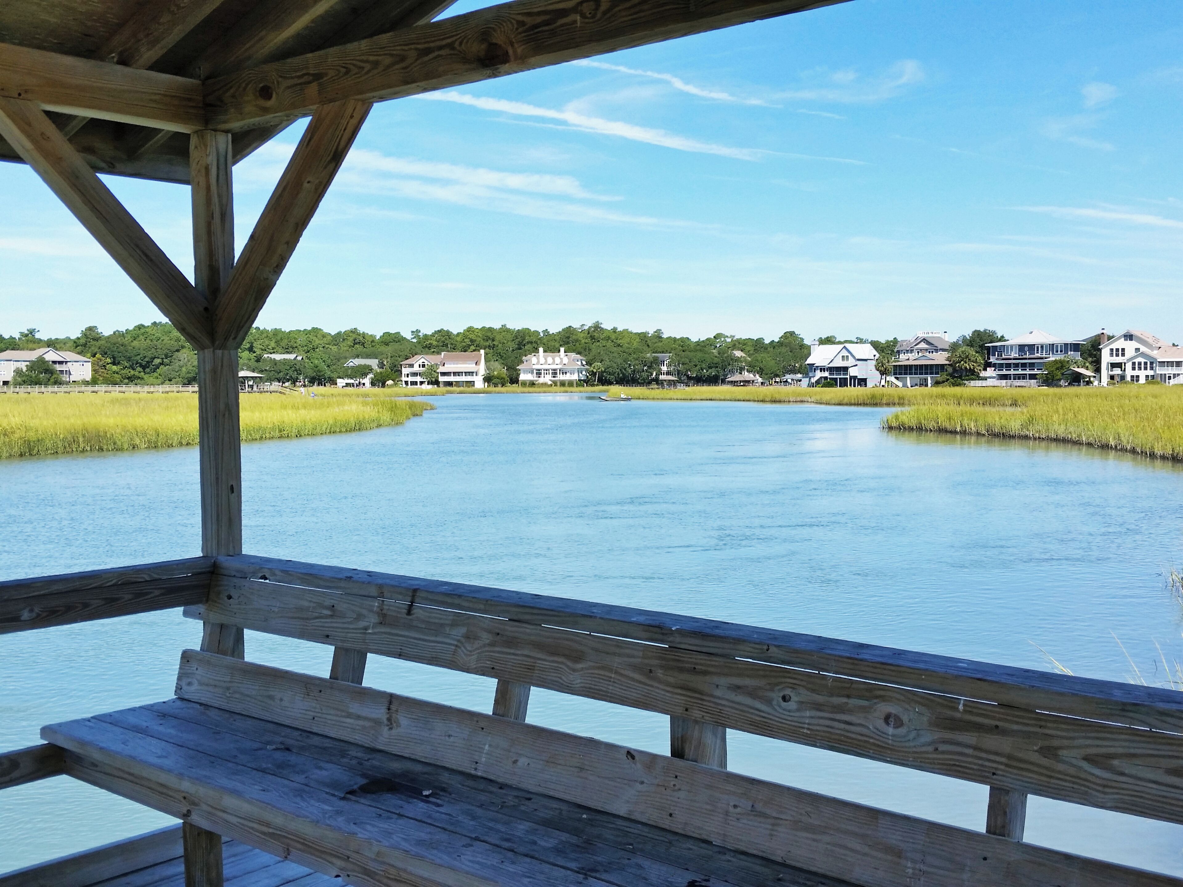 A wooden deck overlooking a calm lake with houses in the background.