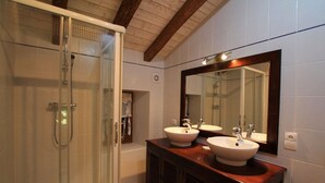 A bathroom with a glass-enclosed shower, two sinks, and a large mirror.