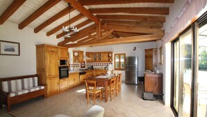 A spacious kitchen with wooden cabinets, a dining table, and a refrigerator.