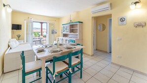 A compact living space with a dining area, kitchenette, and a television mounted on the wall. - Residence a Marinella a 450 mt dal mare  (Golfo Aranci)