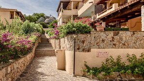 A narrow stone pathway flanked by buildings with balconies, leading to a staircase. - Residence a Marinella a 450 mt dal mare  (Golfo Aranci)