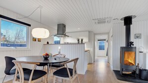 Une cuisine moderne avec des meubles blancs, un îlot central et un poêle à bois.