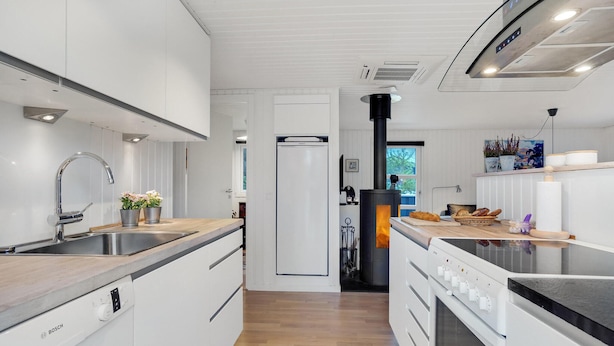 Une cuisine moderne avec des meubles blancs, des appareils en acier inoxydable et des plans de travail en bois.