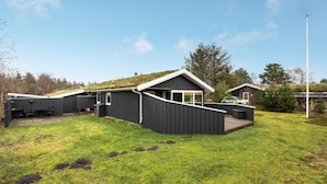 Une maison moderne de plain-pied, dotée d’un toit en pente, d’un patio couvert et d’une petite terrasse.