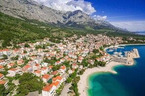 An aerial view of a coastal town with buildings, a beach, and a marina.
